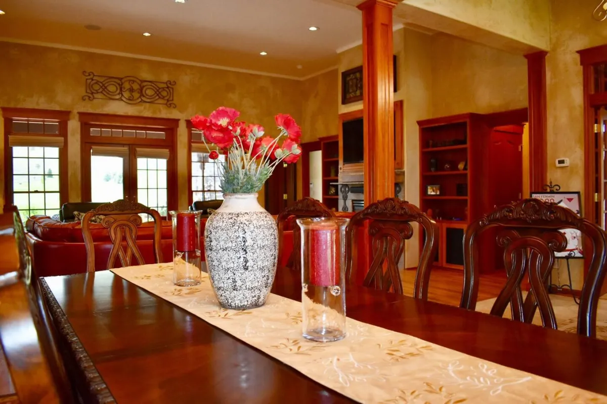 An elegant dining area with a beautifully set dining table, flower vase centerpiece, softly glowing candles, and a decorative wall backdrop. The scene suggests intimate family gatherings, dinner parties, and festive celebrations.