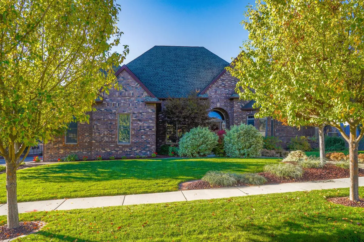 The home’s exterior with a well-tended brick façade, lush green lawn, and decorative trees, leading up a walkway to the entrance. The landscaping is inviting and serene, framing the estate as both a welcoming home and an inspiring place to stay.